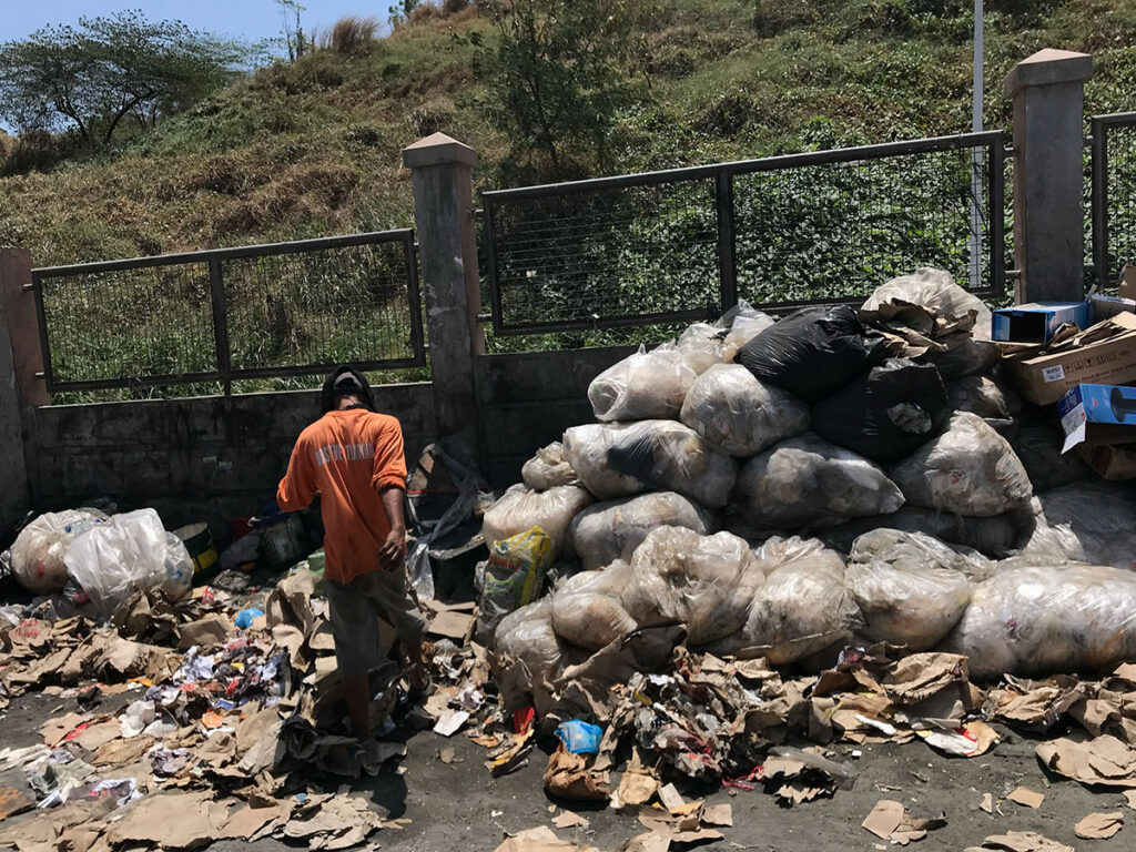 ゴミ山の柵の前にはゴミを漁る男
