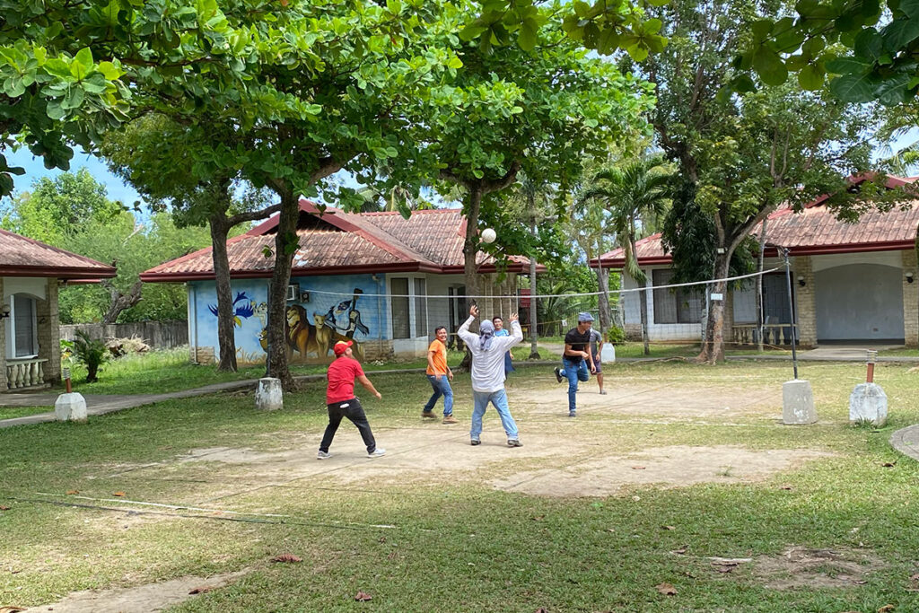 広いキャンパスでバレーボールするフィリピン人