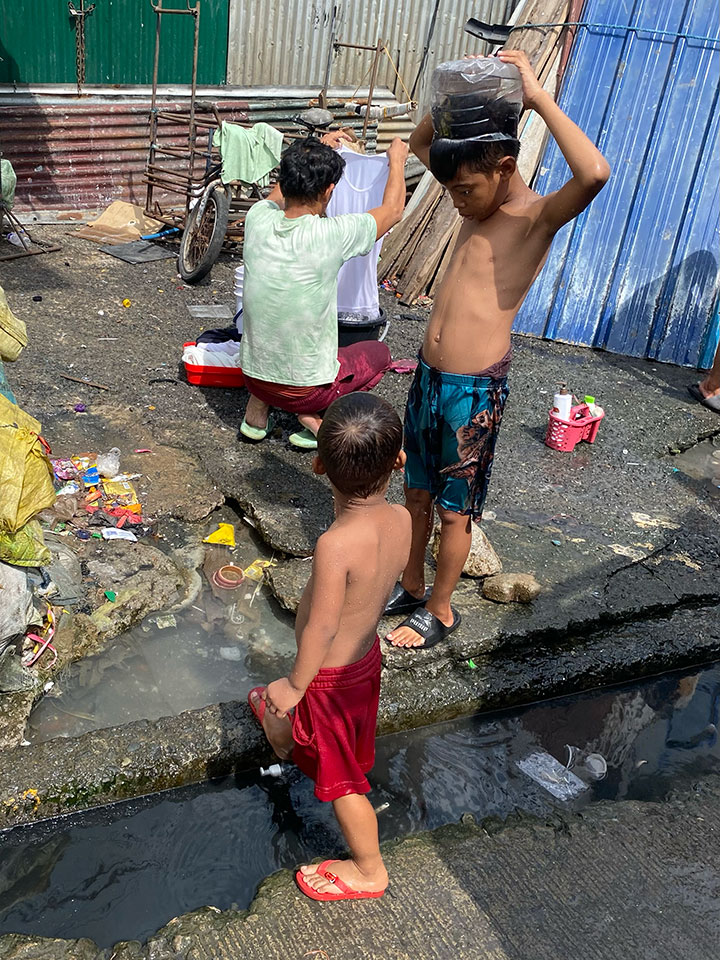 路上で水浴びするスラムの子供たち